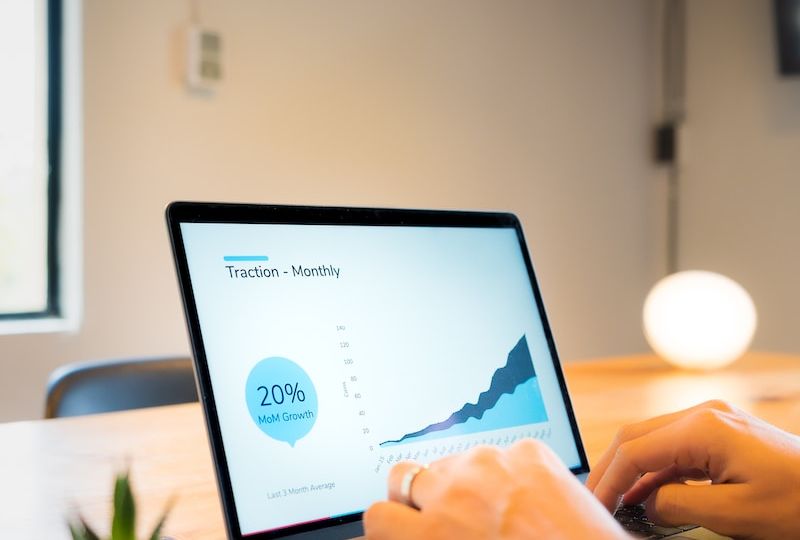 person using macbook pro on brown wooden table