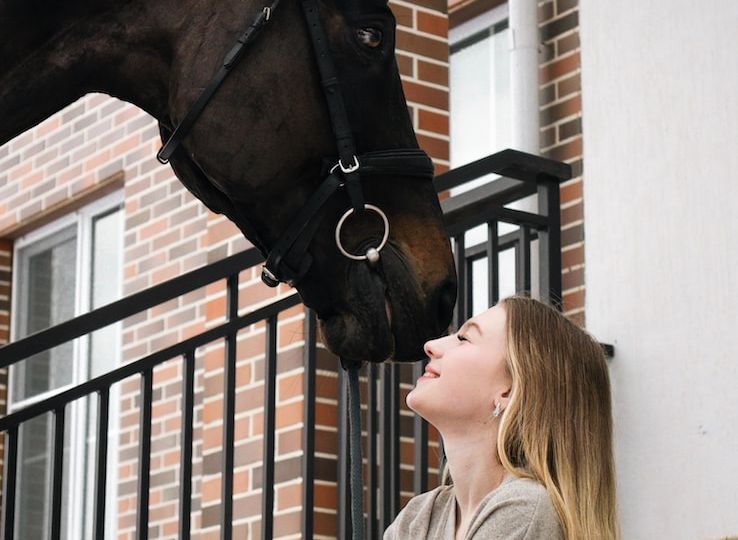 a woman sitting on the steps with a horse on her head