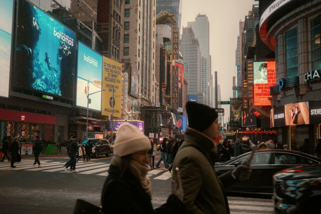 People walk in times square on a cloudy day.