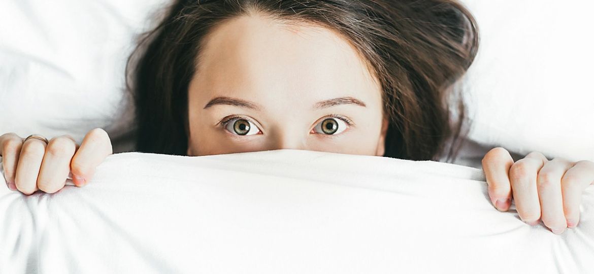 woman covering her face with blanket