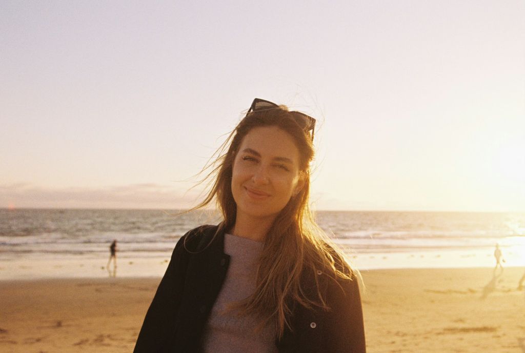 Woman smiles at the beach during sunset.